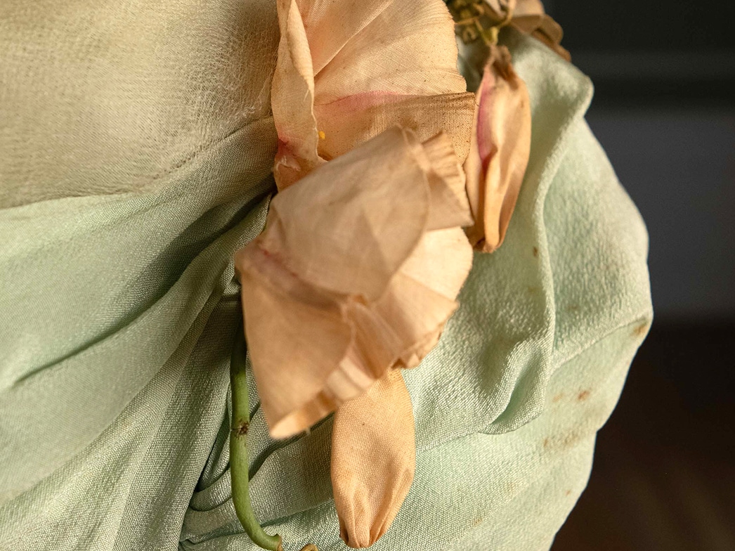 Des fleurs en soie crème pâle et rose ornent l’épaule d’une manche.