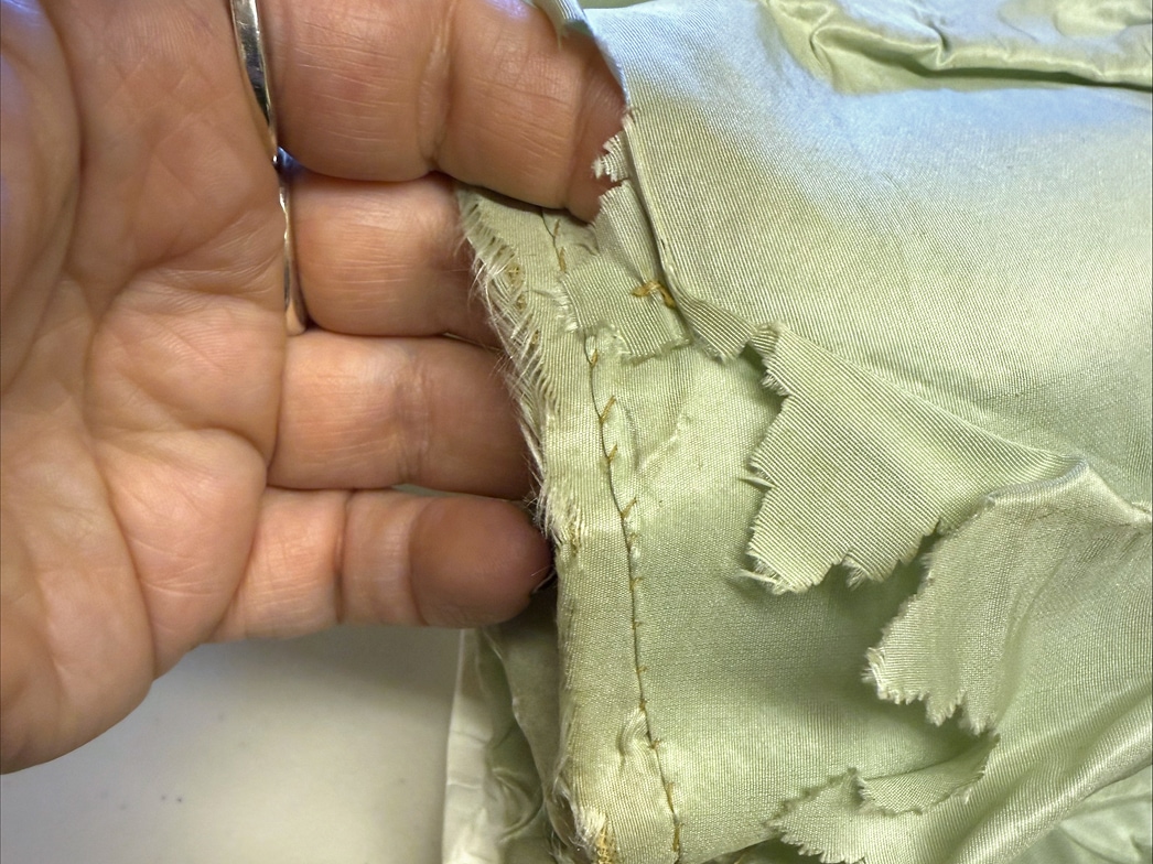 Un gros plan des sous-jupes montre une main tenant plusieurs couches de jupons, dont une avec des découpes irrégulières.