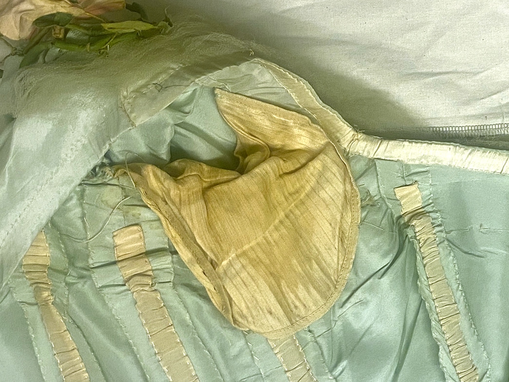 Un gros plan de l’intérieur de la robe, au niveau des aisselles, révèle des coussinets en soie jaunis.