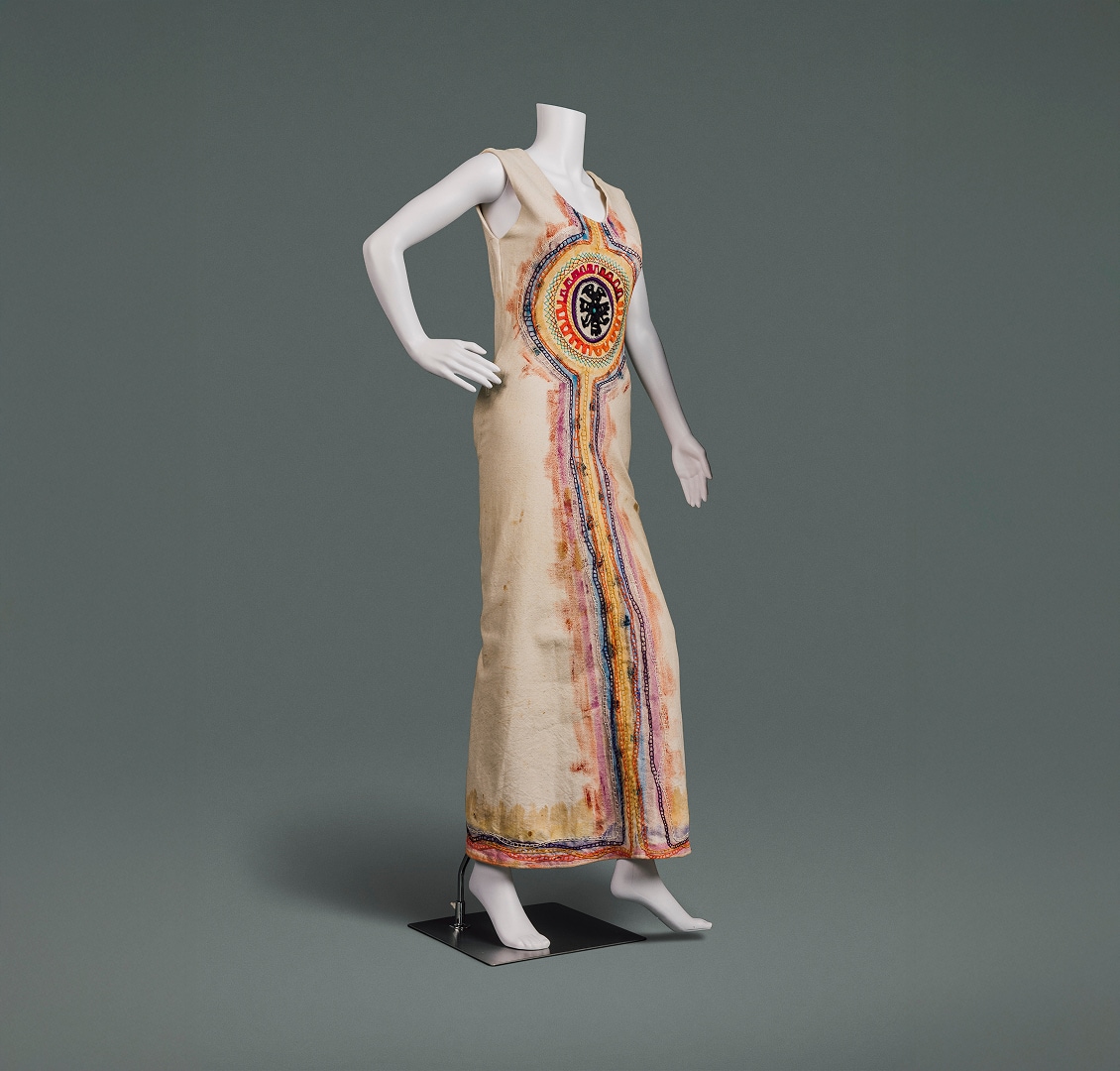 Une robe longue en coton naturel ornée de peintures et de broderies inspirées des traditions de l’art populaire.
