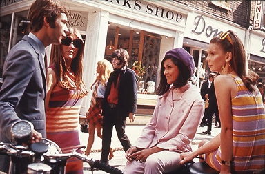 Des hommes et des femmes élégants flânent devant les magasins londoniens.