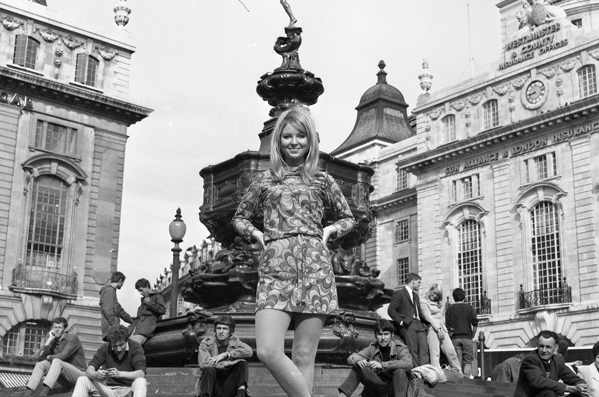 Une mannequin pose en mini-robe à l’extérieur, à Piccadilly, à Londres, près de la statue d’Éros.