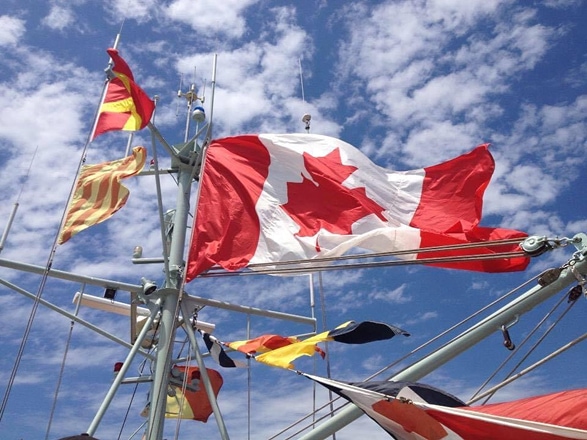Un drapeau canadien, hissé au-dessus d’un voilier, flotte au vent.