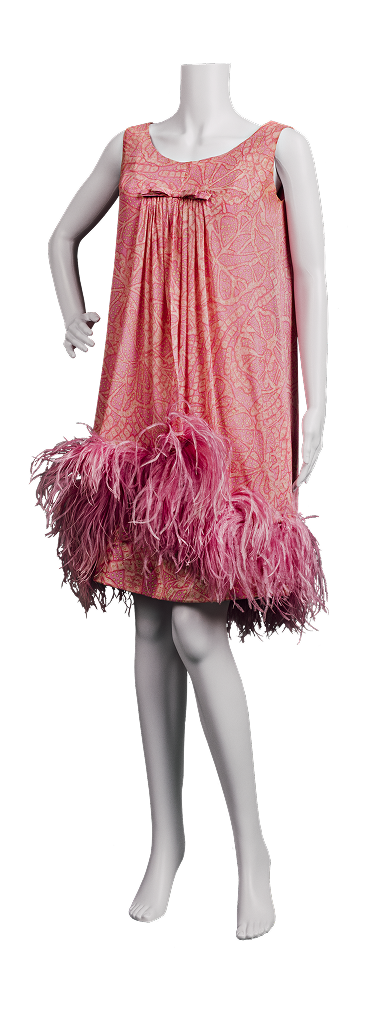 Robe cocktail rose des années 1960, confectionnée en soie foulard et sur-robe en mousseline imprimée de motifs cachemire. Elle présente une coupe trapèze ample et un ourlet court au-dessus du genou, orné de franges de plumes roses.